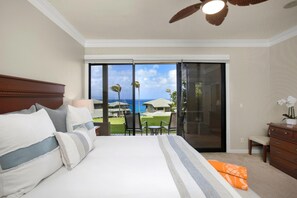 A hotel room with a large bed, a ceiling fan, a view of the ocean, and a balcony with chairs. - Kapalua Bay | Ocean View 6 BR, Sleeps 20 | Car Incl. w/ 6+ Nights | KBV ML-2059 by KBM (Lahaina)