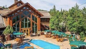 Een lodge met een grote glazen gevel, buitenzwembad en terraszitplaatsen.