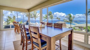 A dining area with a large table and chairs, large windows with a view of the ocean and palm trees. - Kapalua Bay | Ocean View 4 BR, Sleeps 14 | Car Incl. w/ 6+ Nights | KBV ML-2062 by KBM (Lahaina)