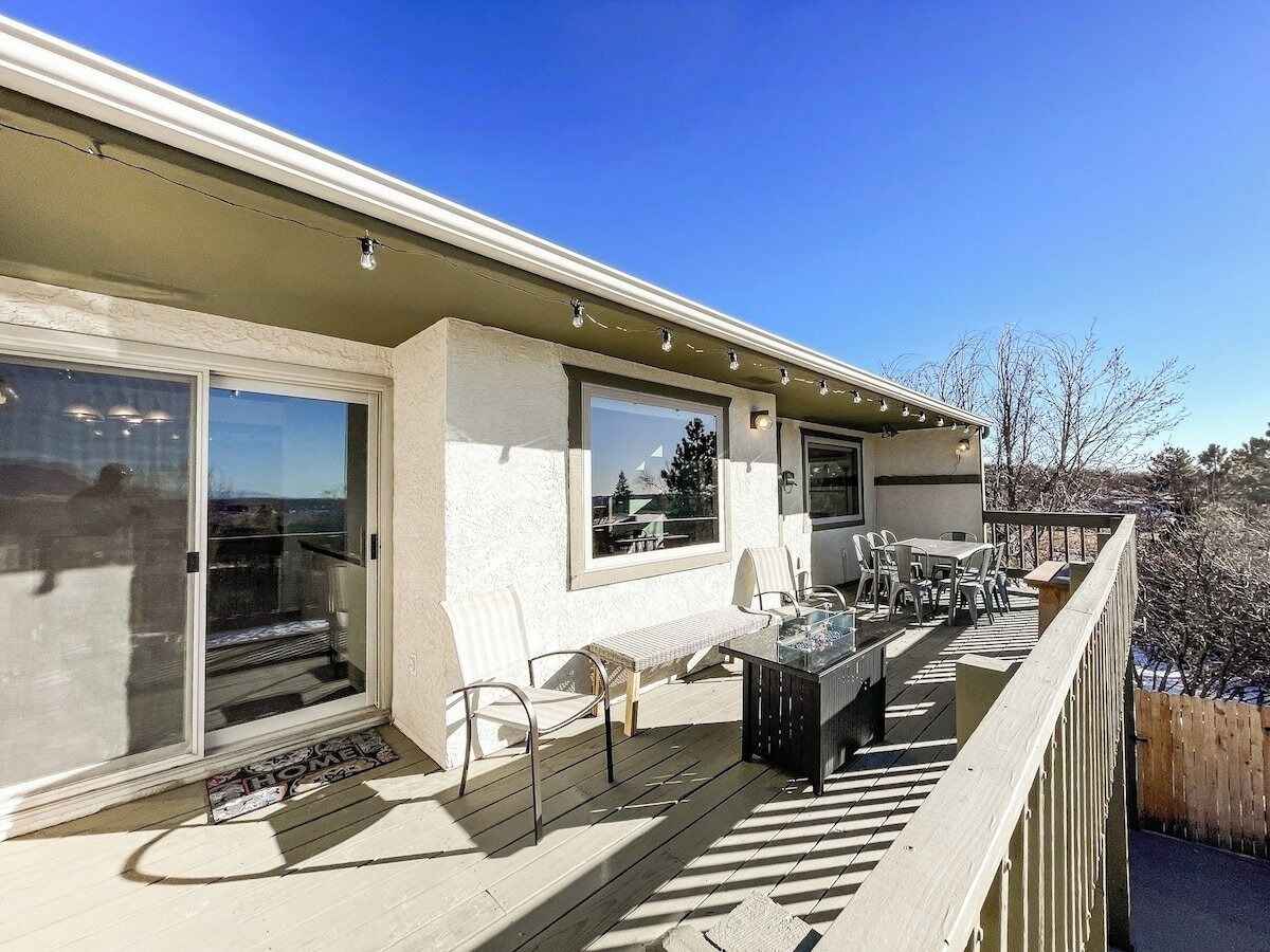 A covered patio with outdoor furniture, a sliding glass door, and a view of the surrounding landscape.