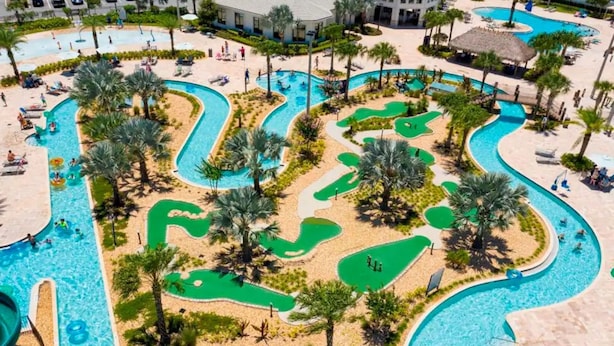 Un resort con varias piscinas, palmeras y un campo de golf.