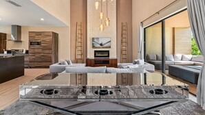 A modern living room with a glass coffee table, a fireplace, and a large window. - Bright and Modern Townhome at Magic Village - Superb Disney Location (Kissimmee)