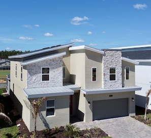 A modern two-story house with a stone facade, a garage, and a small front yard with landscaping. - Modern Oasis Near Shopping n Golf Course w Pool (Davenport)