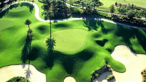An aerial view of a golf course with sand bunkers, palm trees, and a well-maintained green. - Modern Oasis Near Shopping n Golf Course w Pool (Davenport)