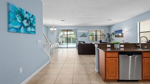 Une cuisine spacieuse équipée d’un lave-vaisselle, un coin repas avec des chaises et une vue sur la piscine.
