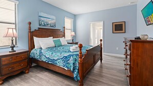 Une chambre à coucher avec un lit en bois, une table de chevet, une commode et une fenêtre avec des stores.
