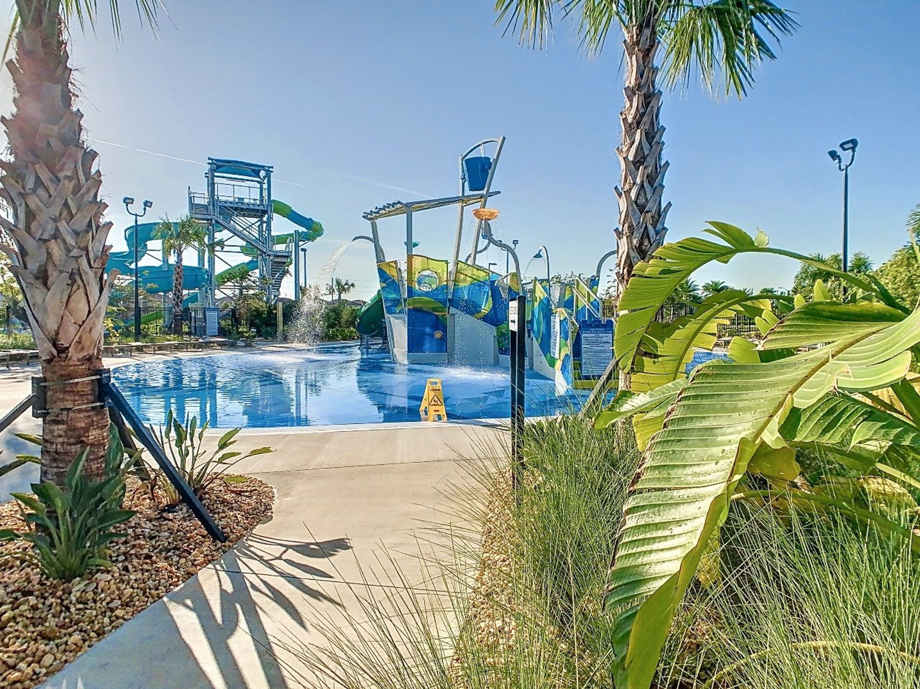 Un parc aquatique avec une piscine, des toboggans et des palmiers.