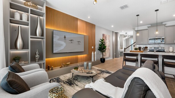 A modern living room with a sofa, coffee table, and decorative items. There is a kitchen area with a dining table and chairs. - Perfect for Children With Epic Themed Bedrooms (Kissimmee)