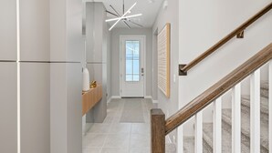 A modern hallway with a wooden staircase, a ceiling light fixture, and a door with a window. - Perfect for Children With Epic Themed Bedrooms (Kissimmee)