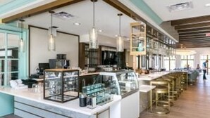 A modern interior with a central counter, glass display cases, and hanging pendant lights.