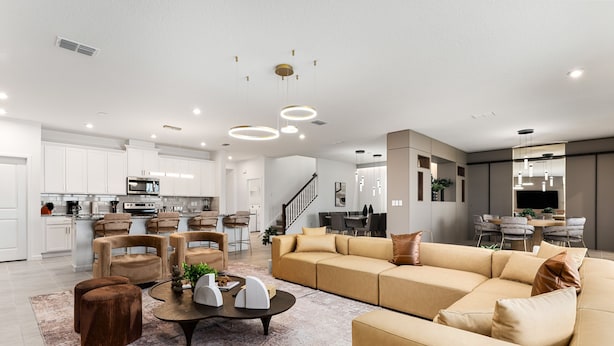 A modern living room with a sectional sofa, a coffee table, and a dining area in the background.