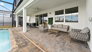A covered outdoor area with a pool, seating, and a view of the surrounding landscape.