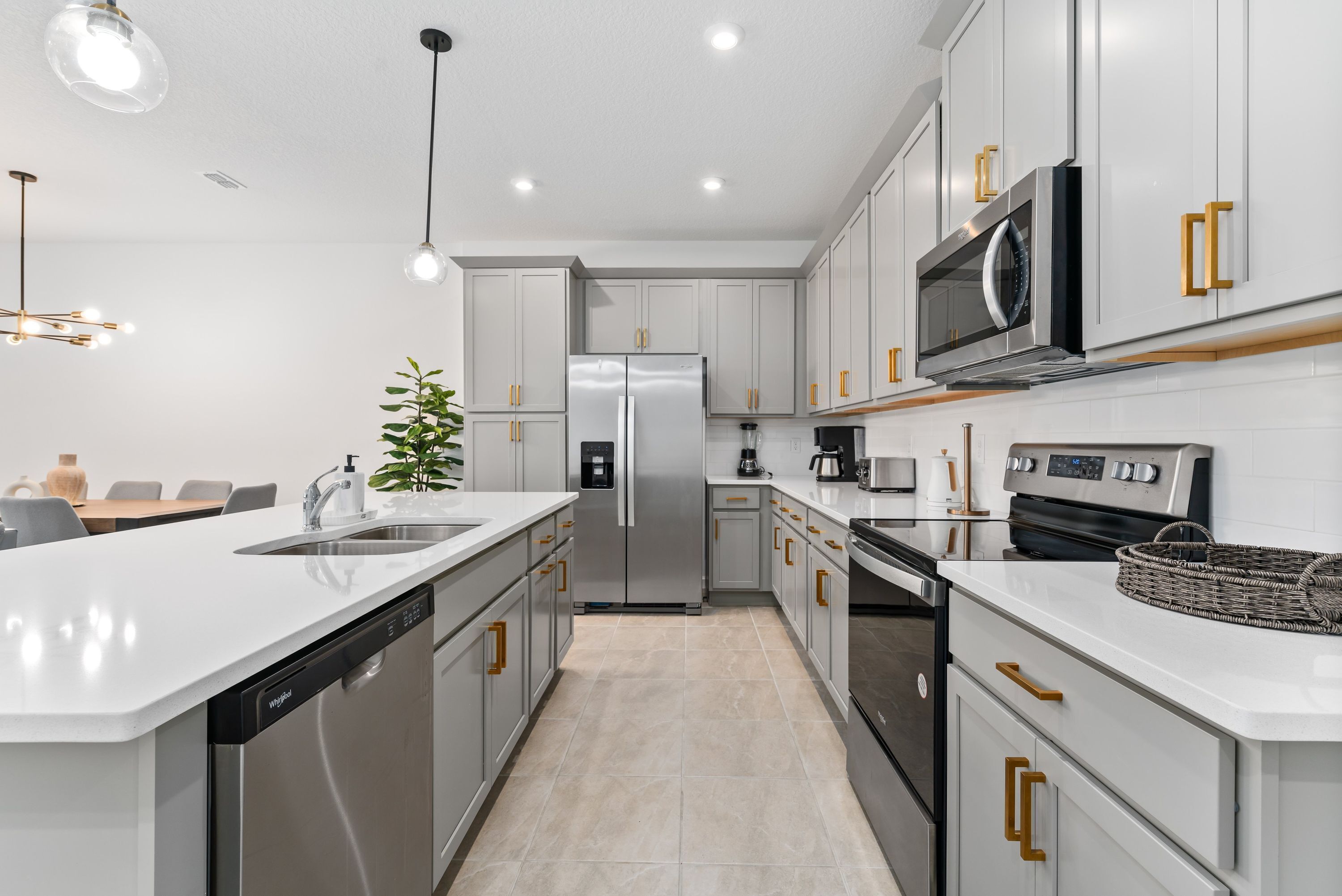 A modern kitchen with stainless steel appliances, white cabinetry, and gold handles.