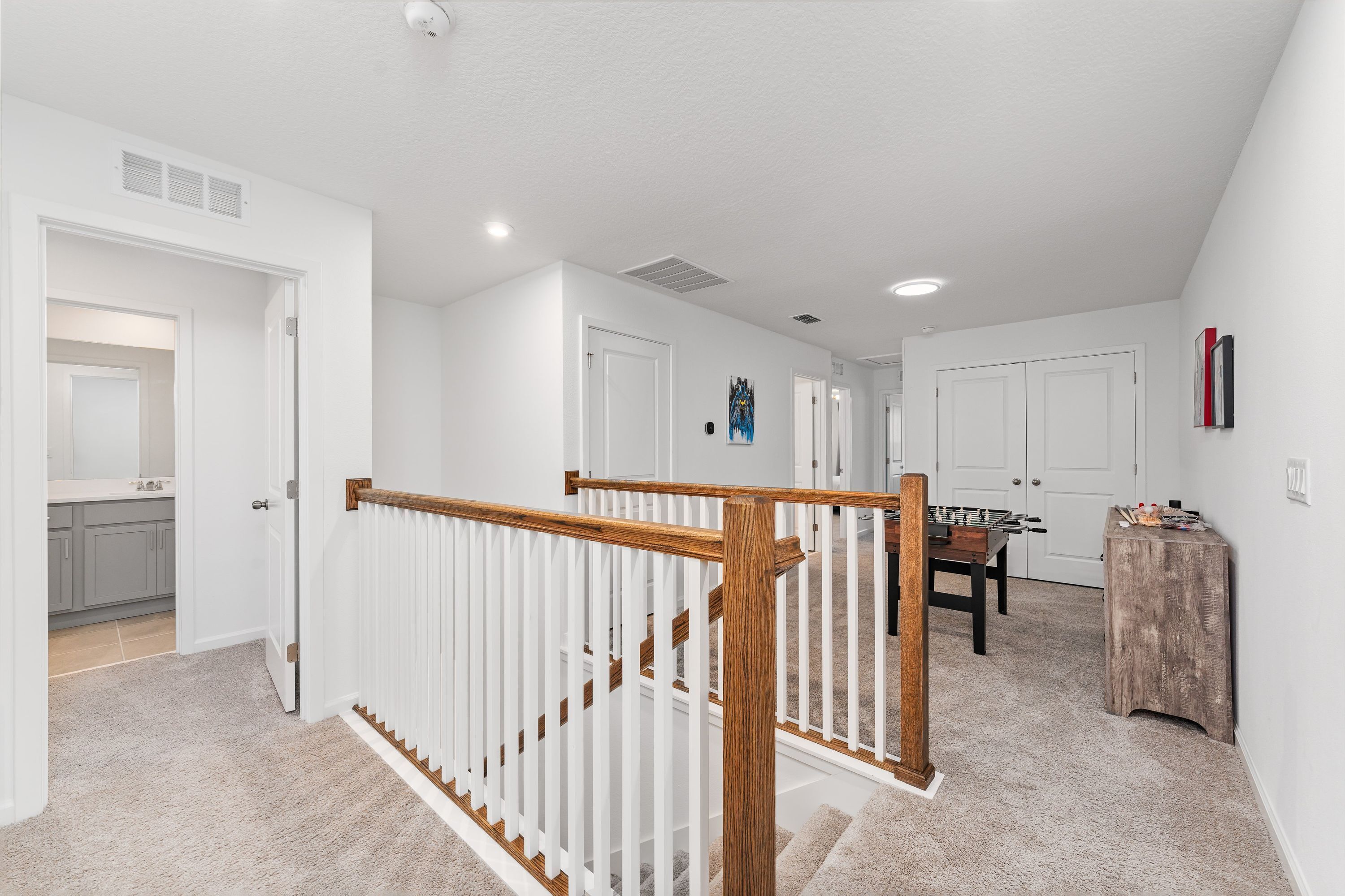 A spacious hallway with white walls, a wooden staircase, and a visible kitchen area.