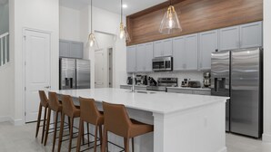 A modern kitchen with a large island, stainless steel appliances, and wooden accents. - Brand New Modern State of the Art Home Sleeps 31 (Kissimmee)