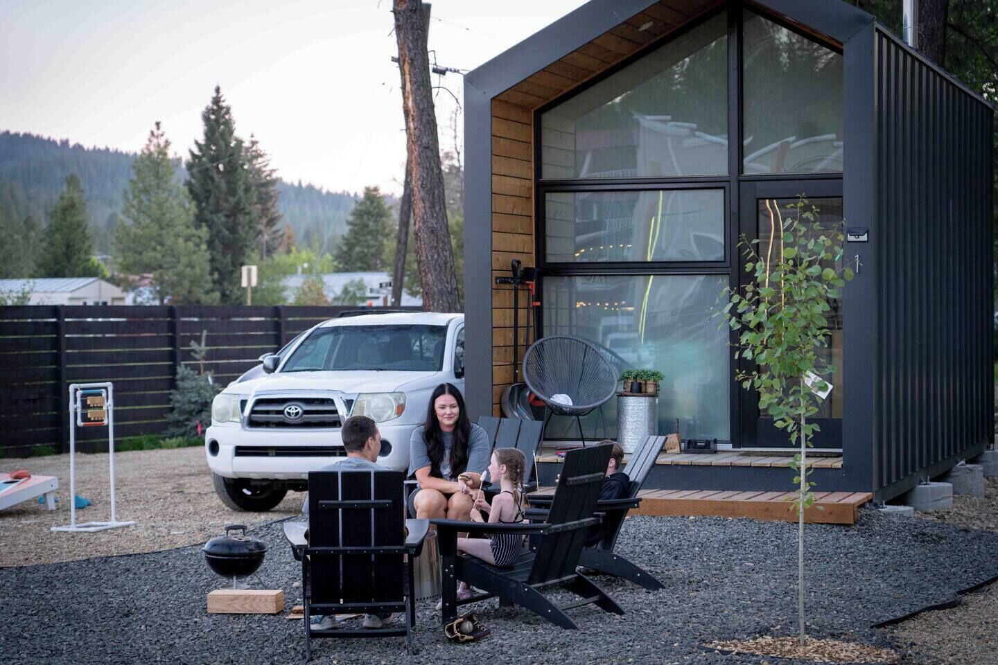 A modern house with large windows, a barbecue grill, and outdoor seating.