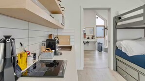 Habitación de hotel compacta con kitchenette, cama con colchón azul y vista al baño.