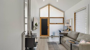 Un salon moderne avec une cheminée, un canapé, une petite table et un téléviseur.