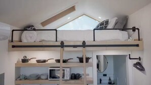 Habitación compacta de dos niveles con literas, kitchenette y tragaluz.