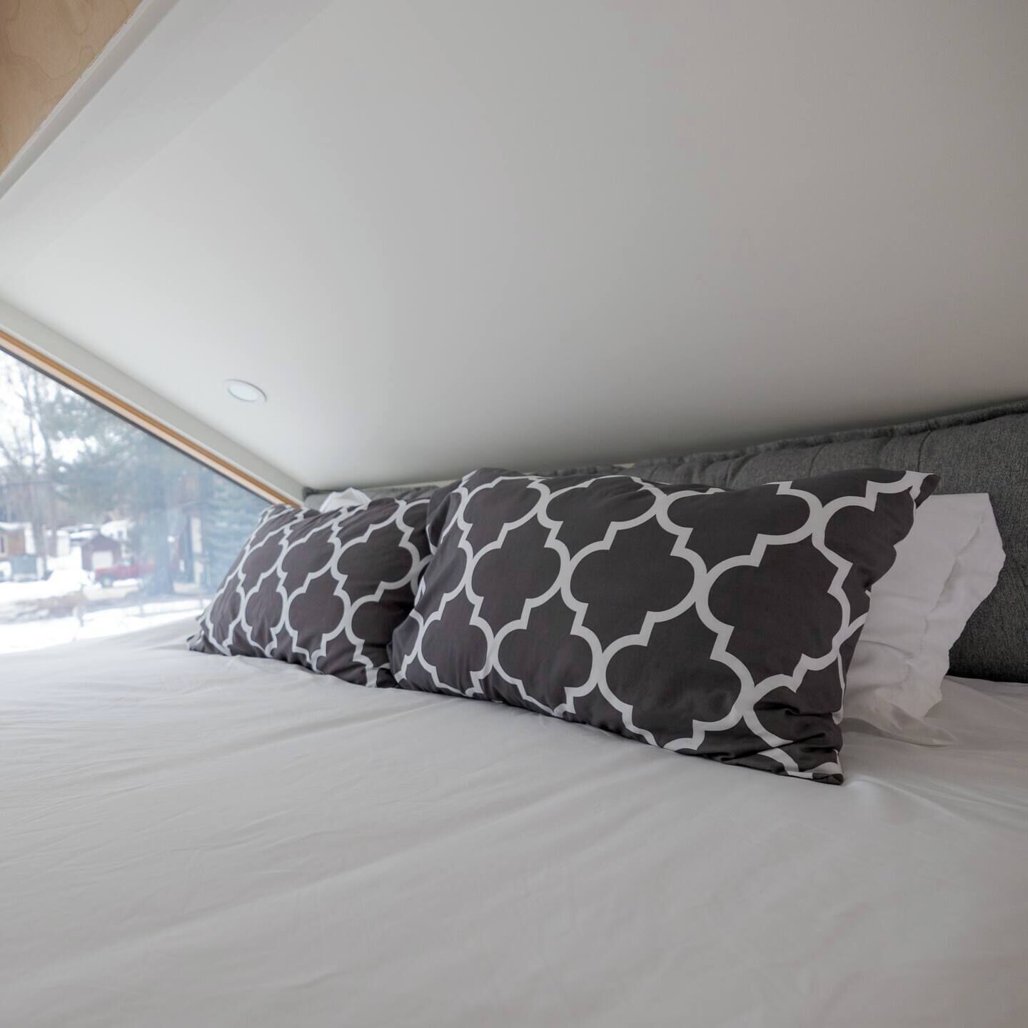Un dormitorio con cama, almohadas y ventana.