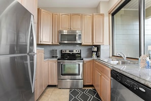 A kitchen with stainless steel appliances, wooden cabinets, a granite countertop, and a dishwasher. - Kapalua Bay | Ocean View 5 BR, Sleeps 16 | Car Incl. w/ 6+ Nights | KBV ML-2071 by KBM (Lahaina)