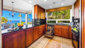 Cozinha com armários de madeira, lava-louças e vista para o oceano.