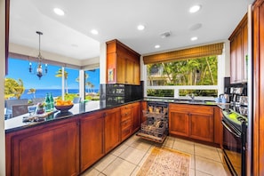 A kitchen with wooden cabinets, a dishwasher, and a view of the ocean. - Kapalua Bay | Ocean View 5 BR, Sleeps 16 | Car Incl. w/ 6+ Nights | KBV ML-2071 by KBM (Lahaina)
