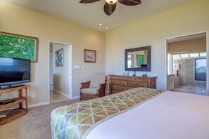 A bedroom with a bed, a TV, a dresser, a chair, and a bathroom visible through an open door. - Kapalua Bay | Ocean View 5 BR, Sleeps 16 | Car Incl. w/ 6+ Nights | KBV ML-2071 by KBM (Lahaina)