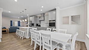 Una cocina moderna con armarios blancos, una isla central y taburetes de bar.