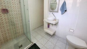 A bathroom with a glass shower enclosure, a white sink with a mirror above it, and a toilet. - Copa Beach Walk – 3 Bedrooms,5 minutes from the beach • Air conditioning + Wi-Fi (Rio de Janeiro)