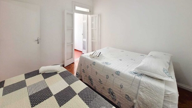 A bedroom with a bed, a checkered rug, and a ceiling fan. - Copa Beach Walk – 3 Bedrooms,5 minutes from the beach • Air conditioning + Wi-Fi (Rio de Janeiro)
