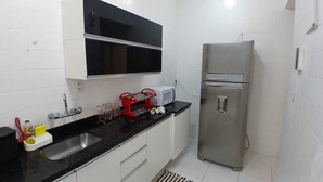 A compact kitchen with a black countertop, white cabinets, a stainless steel refrigerator, and a microwave on the counter. - Copa Beach Walk – 3 Bedrooms,5 minutes from the beach • Air conditioning + Wi-Fi (Rio de Janeiro)