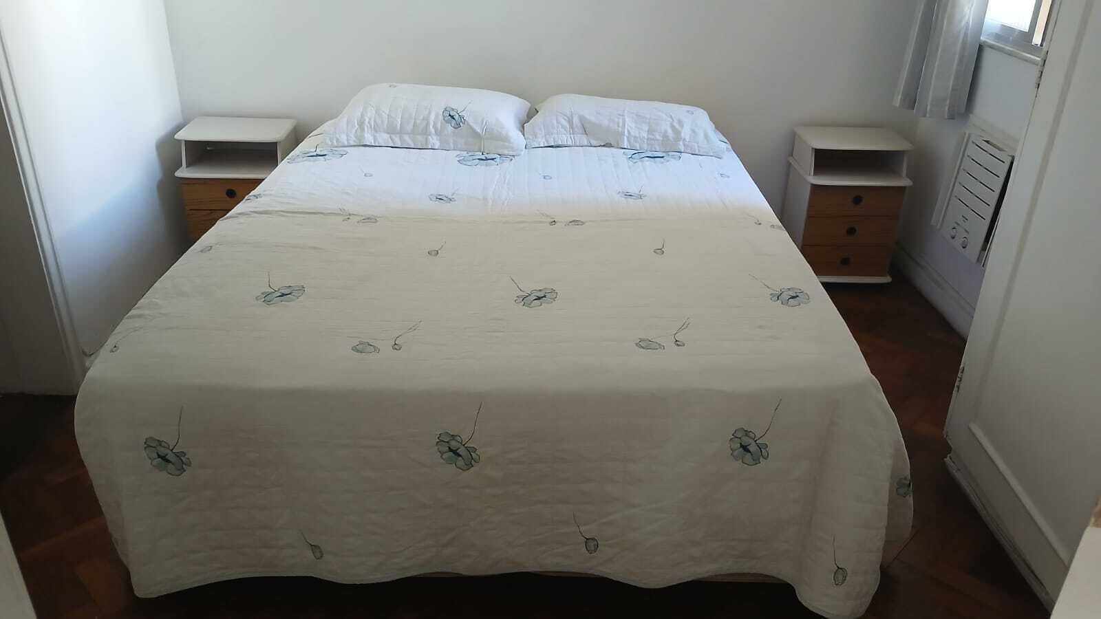 A bedroom with a bed, two bedside tables, and a window.