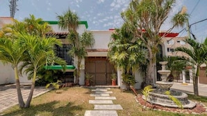 A residential building with a front garden, palm trees, a stone pathway, and a fountain. - Villa Mexico Familiar Centro Cancun (Cancún)
