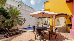 A pool area with a table and chairs, a lounge chair, and an umbrella. - Villa Mexico Familiar Centro Cancun (Cancún)