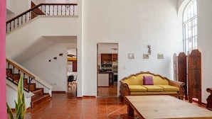 A spacious living area with a wooden staircase, a yellow sofa, and a dining table. - Villa Mexico Familiar Centro Cancun (Cancún)