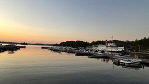 A marina with boats docked, a police boat, and a white building with a red chimney. - Luxury Muskoka Beach Retreat, Games Room & Hot Tub (Gravenhurst)