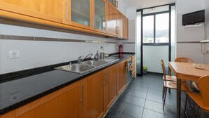 Eine Küche mit Holzausstattung, einer schwarzen Arbeitsplatte, einem Spülbecken und einem Essbereich mit Stühlen und einem Tisch.