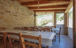 A dining area with a stone wall, wooden ceiling, and large windows. - Stunning home in Perdifumo with house a panoramic view (Perdifumo)