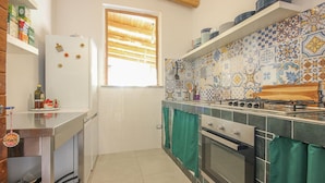 A compact kitchen with a refrigerator, oven, and stove, tiled backsplash, and a window with blinds. - Stunning home in Perdifumo with house a panoramic view (Perdifumo)