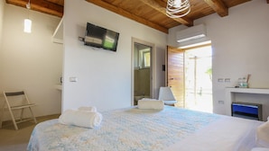 A bedroom with a bed, a television mounted on the wall, a chair, and a bathroom visible through an open door. - Stunning home in Perdifumo with house a panoramic view (Perdifumo)