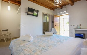 A bedroom with a bed, a television mounted on the wall, a chair, and a bathroom visible through an open door. - Stunning home in Perdifumo with house a panoramic view (Perdifumo)