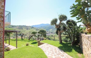 A courtyard with a stone pathway, cacti, and a view of distant hills. - Stunning home in Perdifumo with house a panoramic view (Perdifumo)