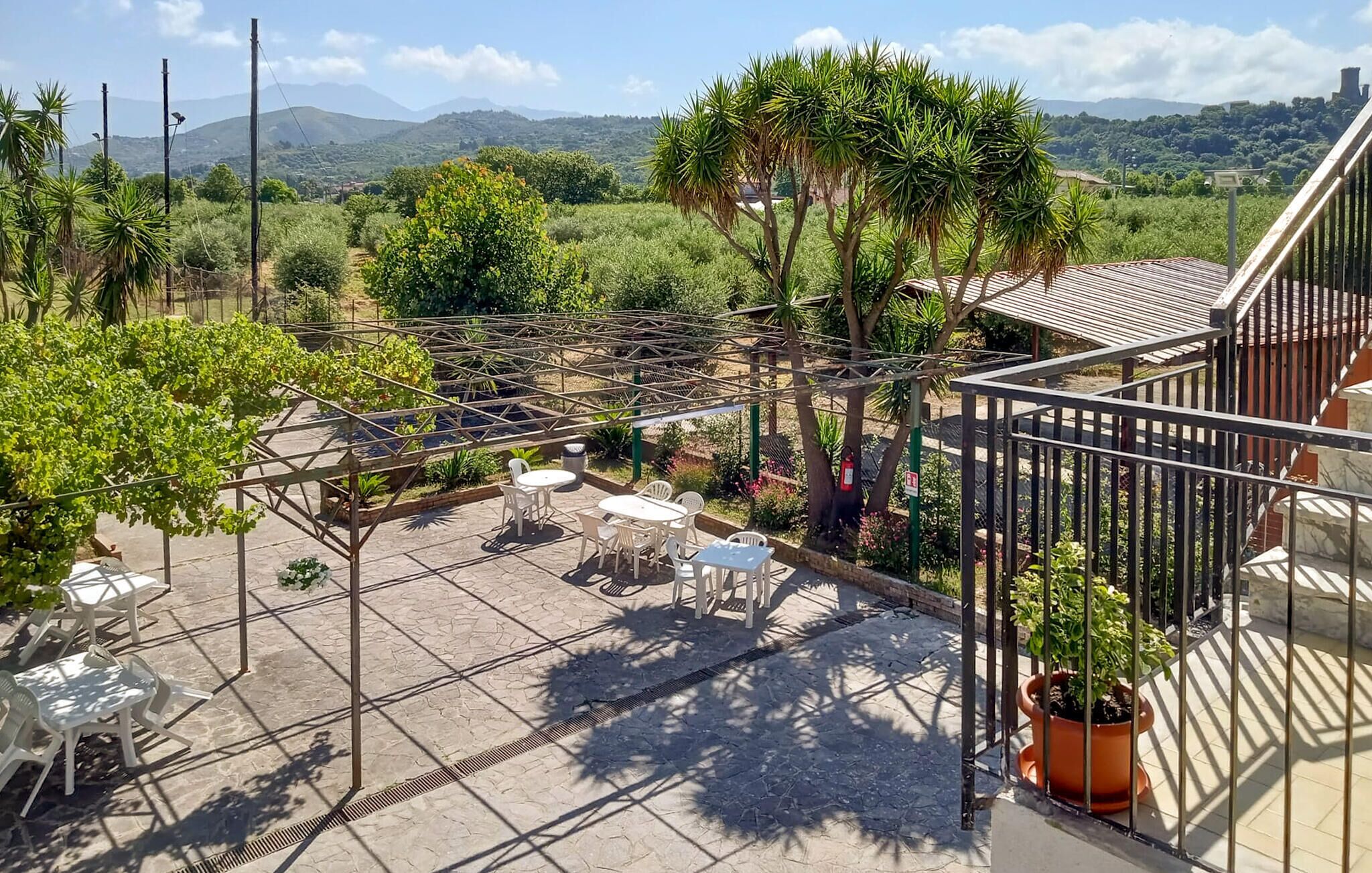 A terrace with a pergola, outdoor seating, and a view of the countryside.