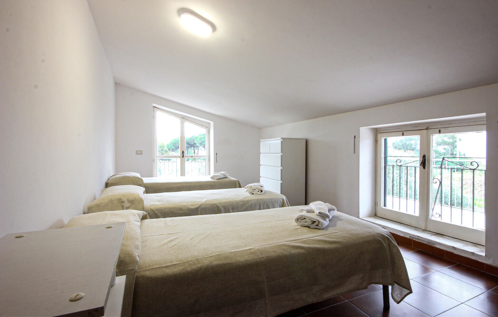 Ein Zimmer mit zwei Betten, einem Kleiderschrank und einem Fenster mit Balkon.