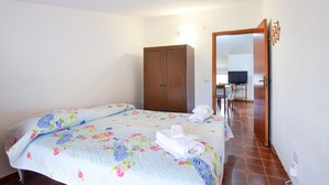 A bedroom with two beds, a wardrobe, a desk with a chair, and a television. - Stunning apartment in Casal Velino with WiFi (Casal Velino)