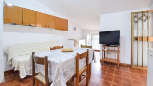 A compact living space with a dining table, chairs, a television on a stand, and a kitchenette in the background. - Stunning apartment in Casal Velino with WiFi (Casal Velino)