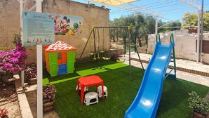 A children's play area with a slide, swings, and a small house. - Stunning apartment in Casal Velino with WiFi (Casal Velino)
