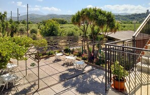 Una terraza con pérgola, mobiliario exterior y vistas a un paisaje exuberante con montañas.