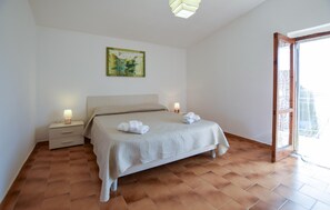 Ein Schlafzimmer mit einem Bett, zwei Nachttischen, einem Bild an der Wand und Blick durch eine offene Tür.